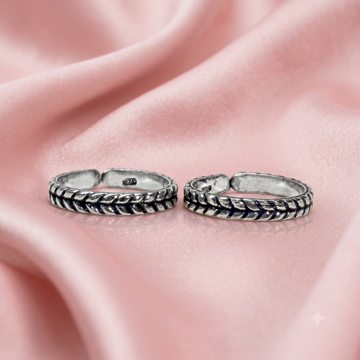 Two silver-toned textured toe rings with a braided or woven pattern