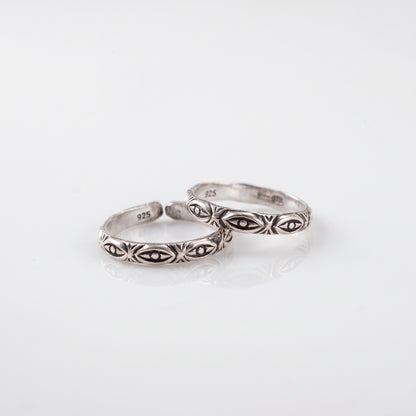 Two silver rings with engraved geometric and floral patterns, displayed on a clean white reflective surface.