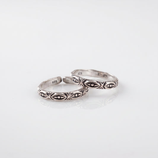Two silver rings with engraved geometric and floral patterns, displayed on a clean white reflective surface.