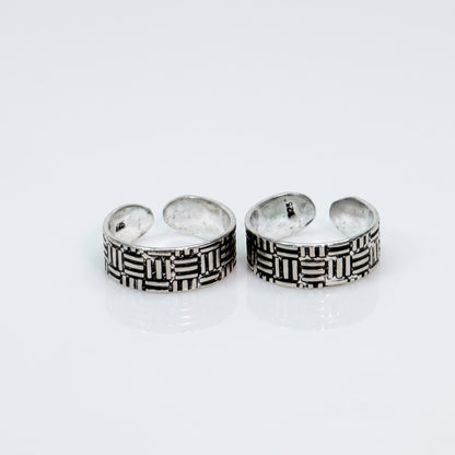A pair of silver-toned open toe rings with a textured basketweave pattern, displayed on a clean white reflective surface.